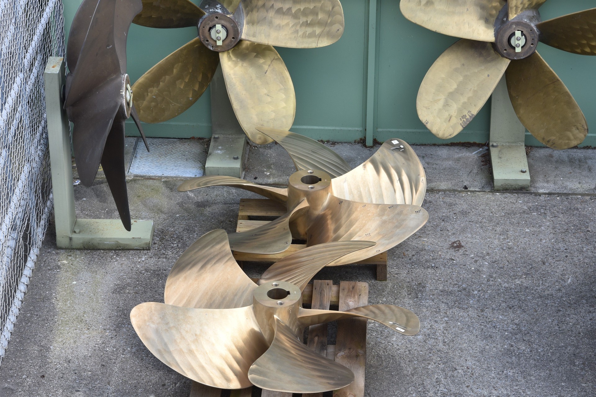 Ships’ or boats’ brass propellers with five blades exposed in the yard of shipyard.